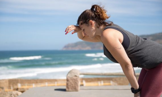 A woman rests after exercise, overlooking the ocean in Portugal's scenic seascape.